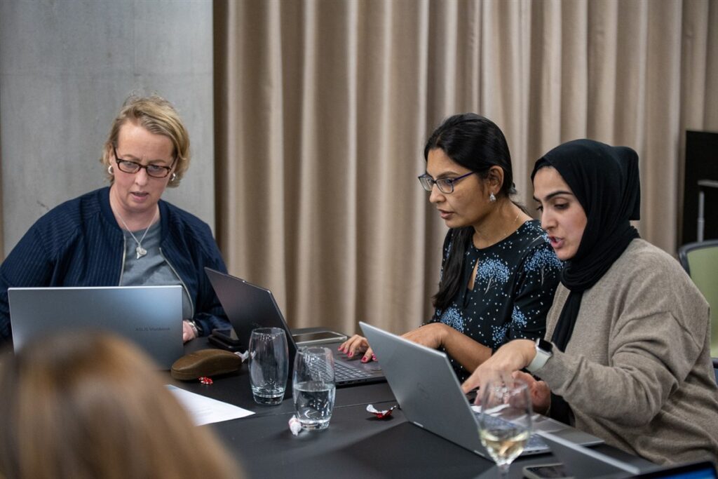 Three learners working together at laptops during the Supermums AI Hackathon