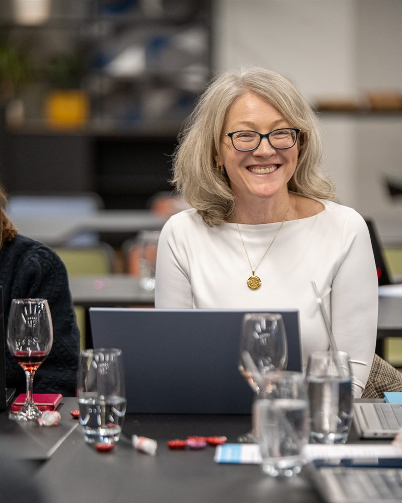 A smiling learner working at her laptop at a Supermums AI event